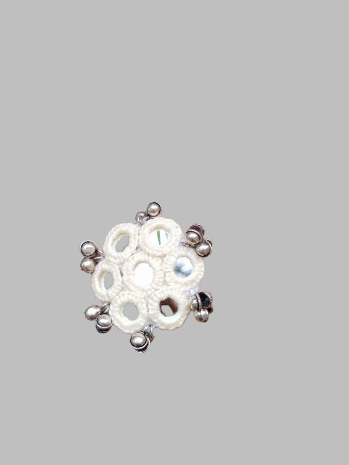 Hand wearing a decorative ring with green leaves in the background