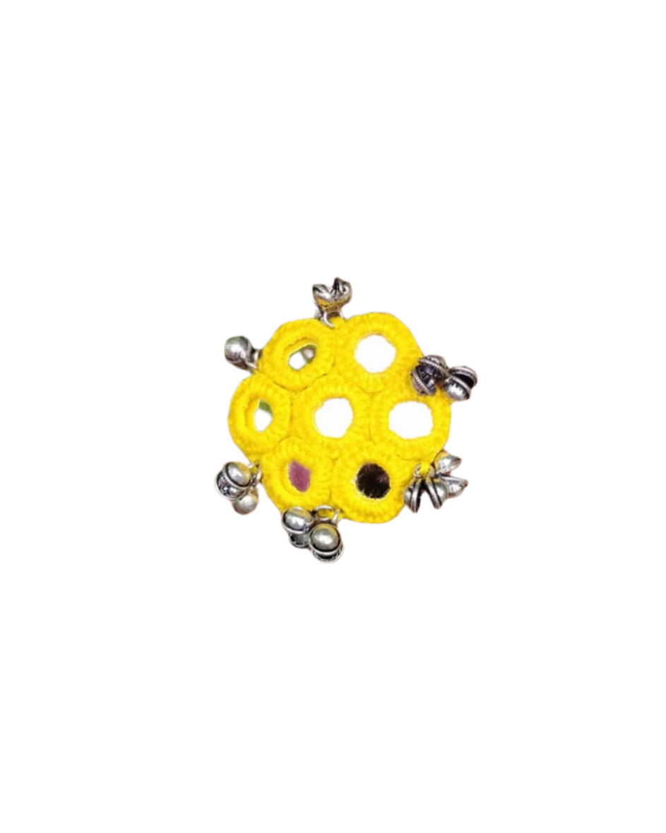 Hand wearing a yellow ring with silver accents against a green leafy background
