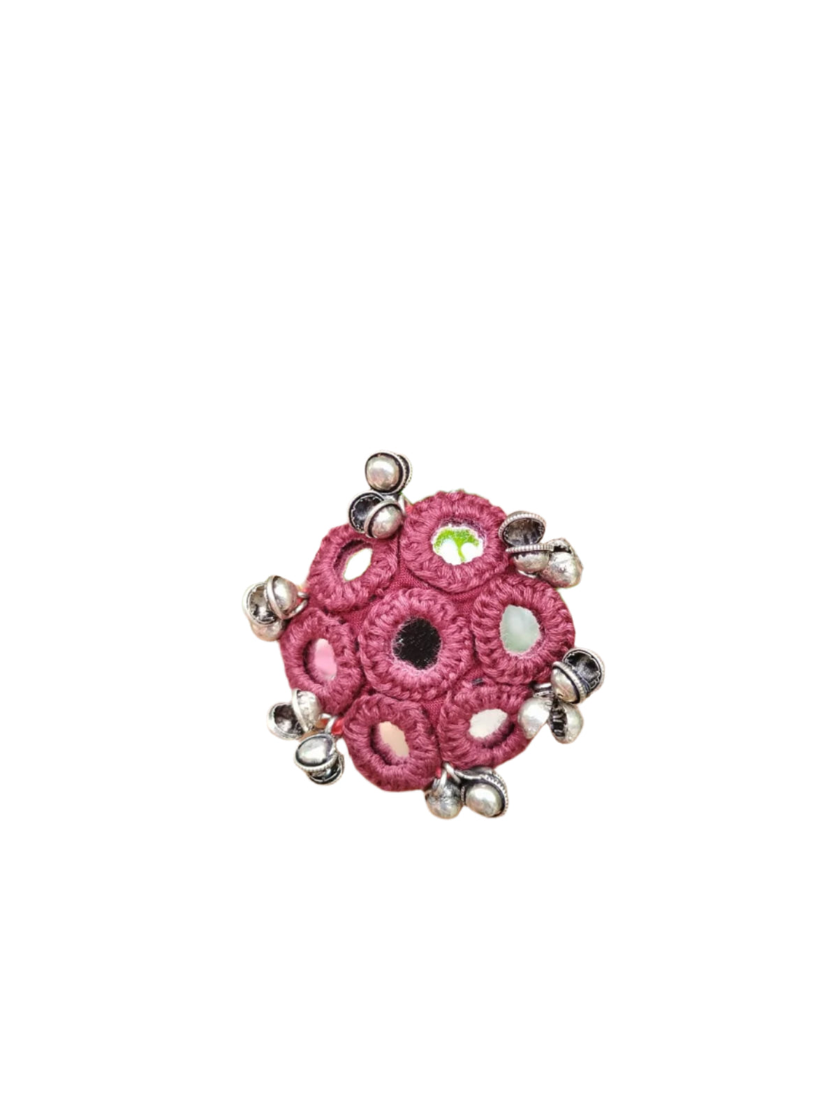 Pink crocheted ring with silver beads on a hand against a green leafy background