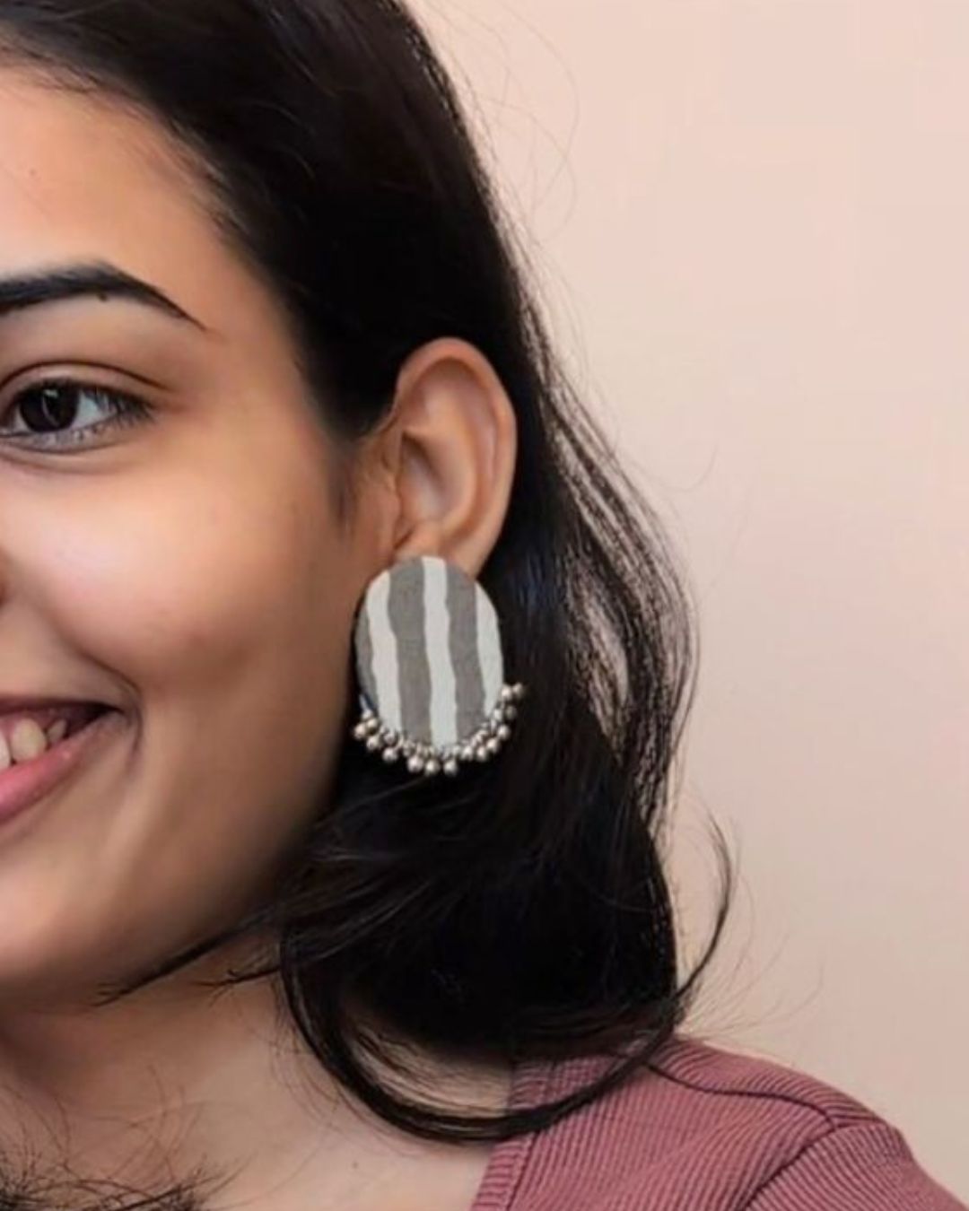Woman wearing a striped earring with a plain background