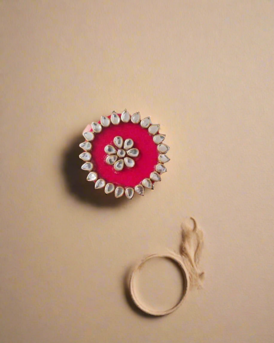 Palm wearing red round finger ring with kundan border on white backdrop