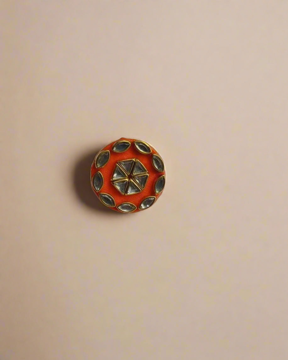 Orange finger ring with kundan details and border on white backdrop