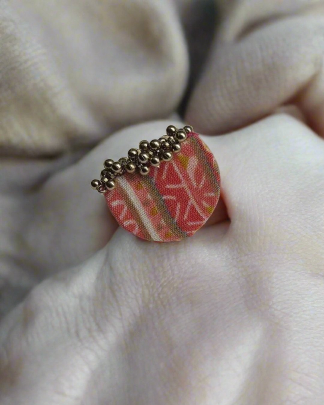 Pink printed semi round finger ring with silver beads on white backdrop