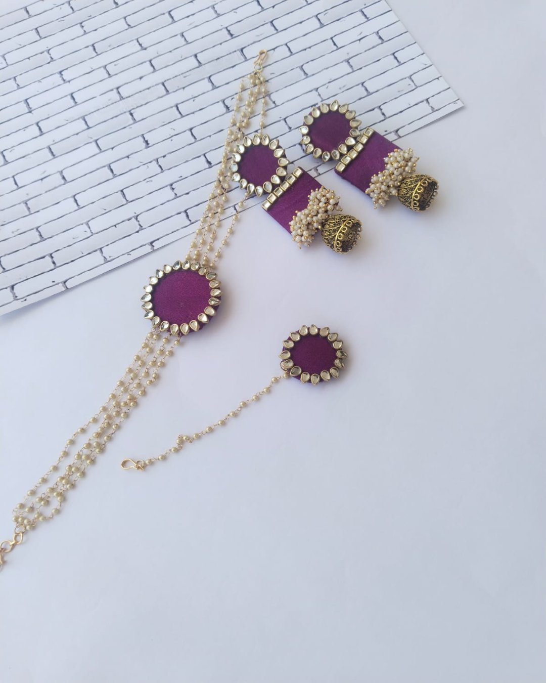 Purple choker necklace with kundan details and matching earrings and tika on white backdrop