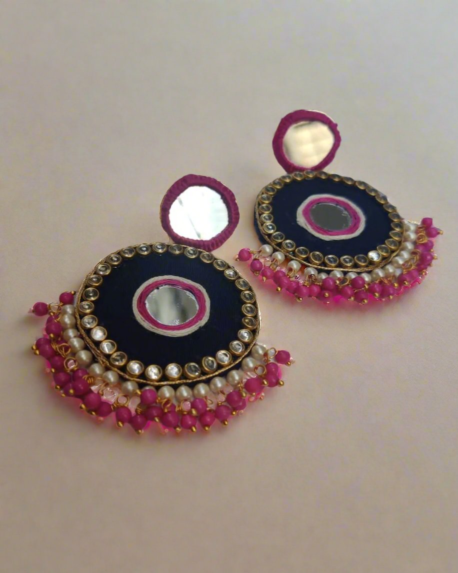 Dark pink and black mirror round earrings with beads and kundan on border on a white backdrop