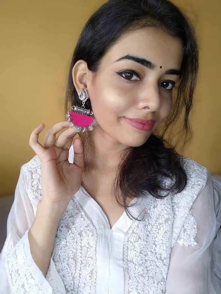 Indian girl smiling wearing white kurti with pink jhumka earrings with metal charms