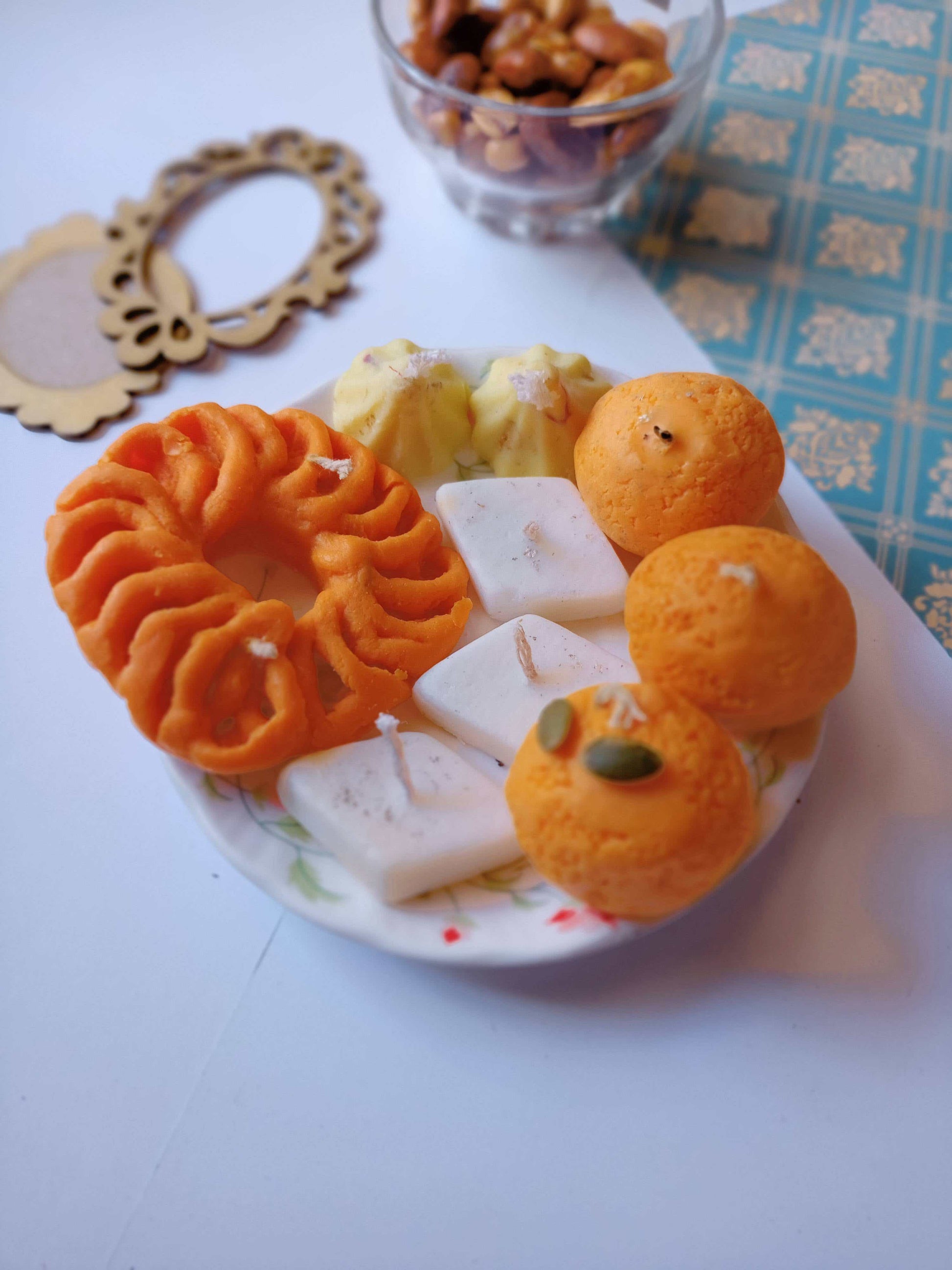 Indian sweets shaped soy wax candles arranged in a plate with props around