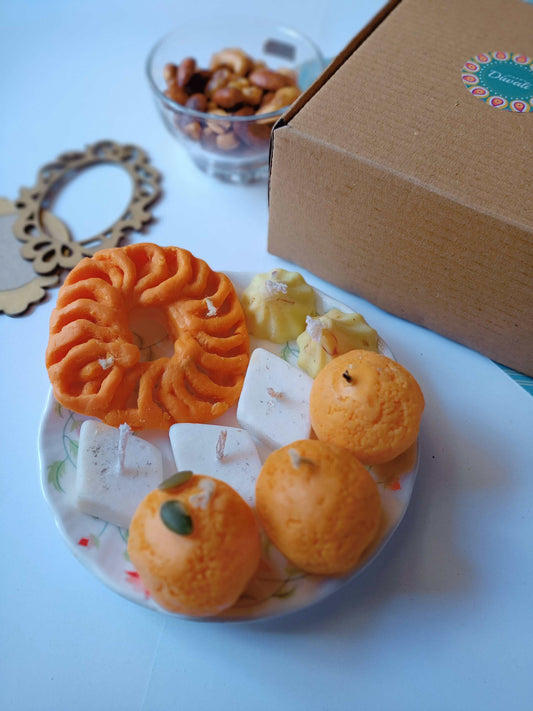 Indian sweets shaped soy wax candles arranged in a plate with props around