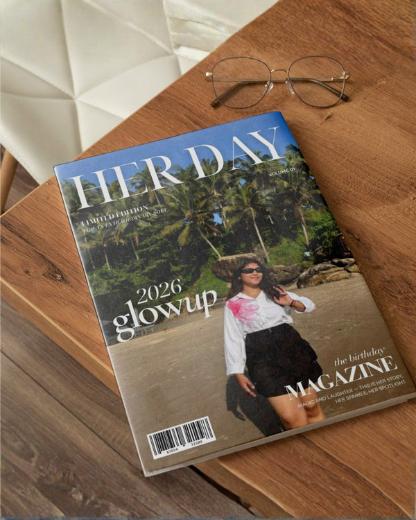 Magazine titled 'Her Day' on a wooden surface with sunglasses