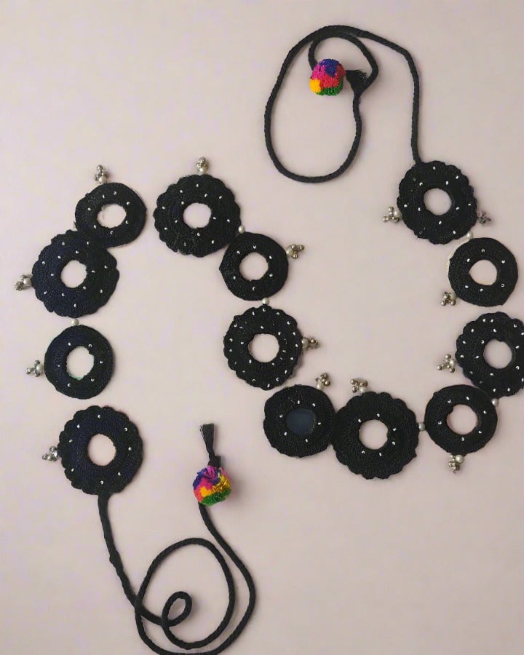 Black weaved round with mirror and beads fabric kamarband on white backdrop