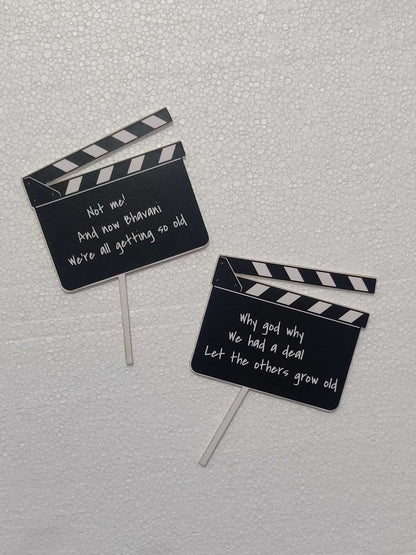 Two black and white film role friends TV inspired cake toppers with messages on white backdrop