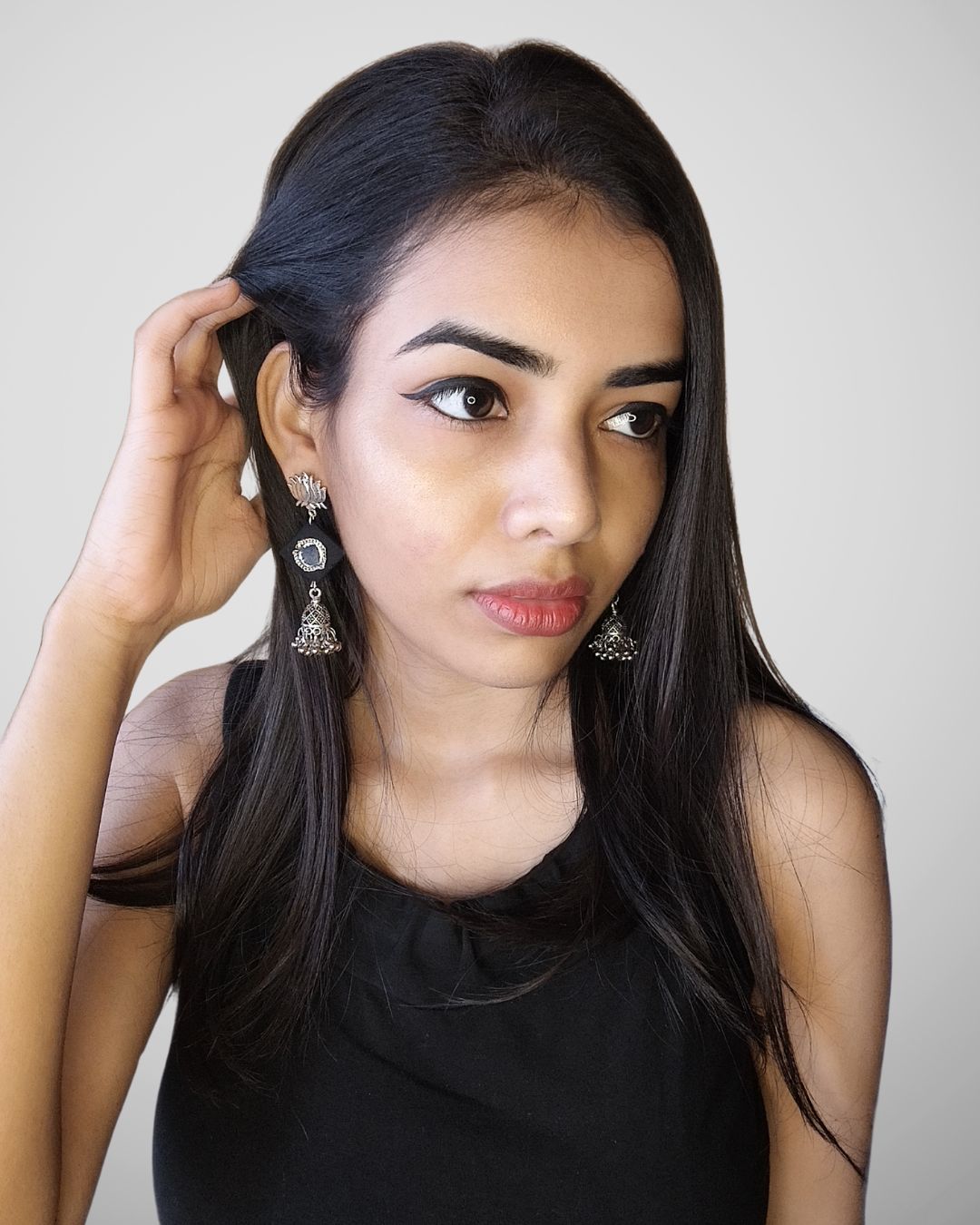 An Indian girl wearing black outfit showing black and silver earrings 
