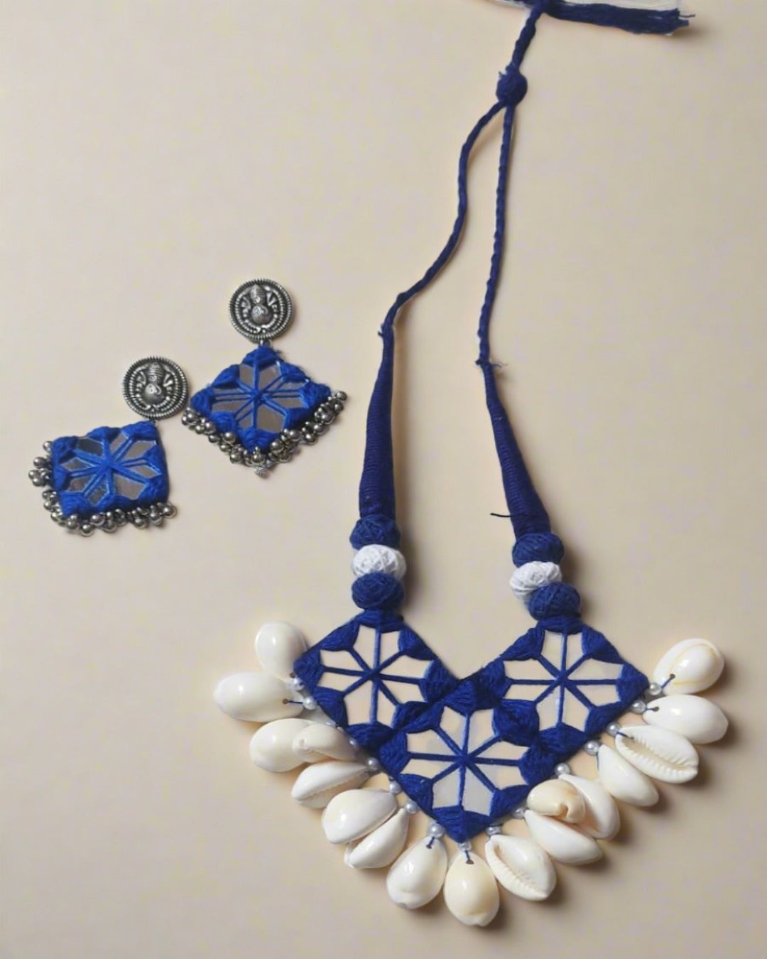 Dark blue necklace with mirror and white sea shells details on white backdrop