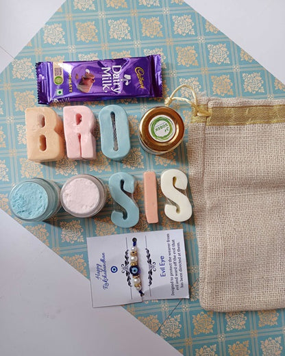 Bro Sis alphabets soaps in blue and pink flatlay with evil eye rakhi and jute bag