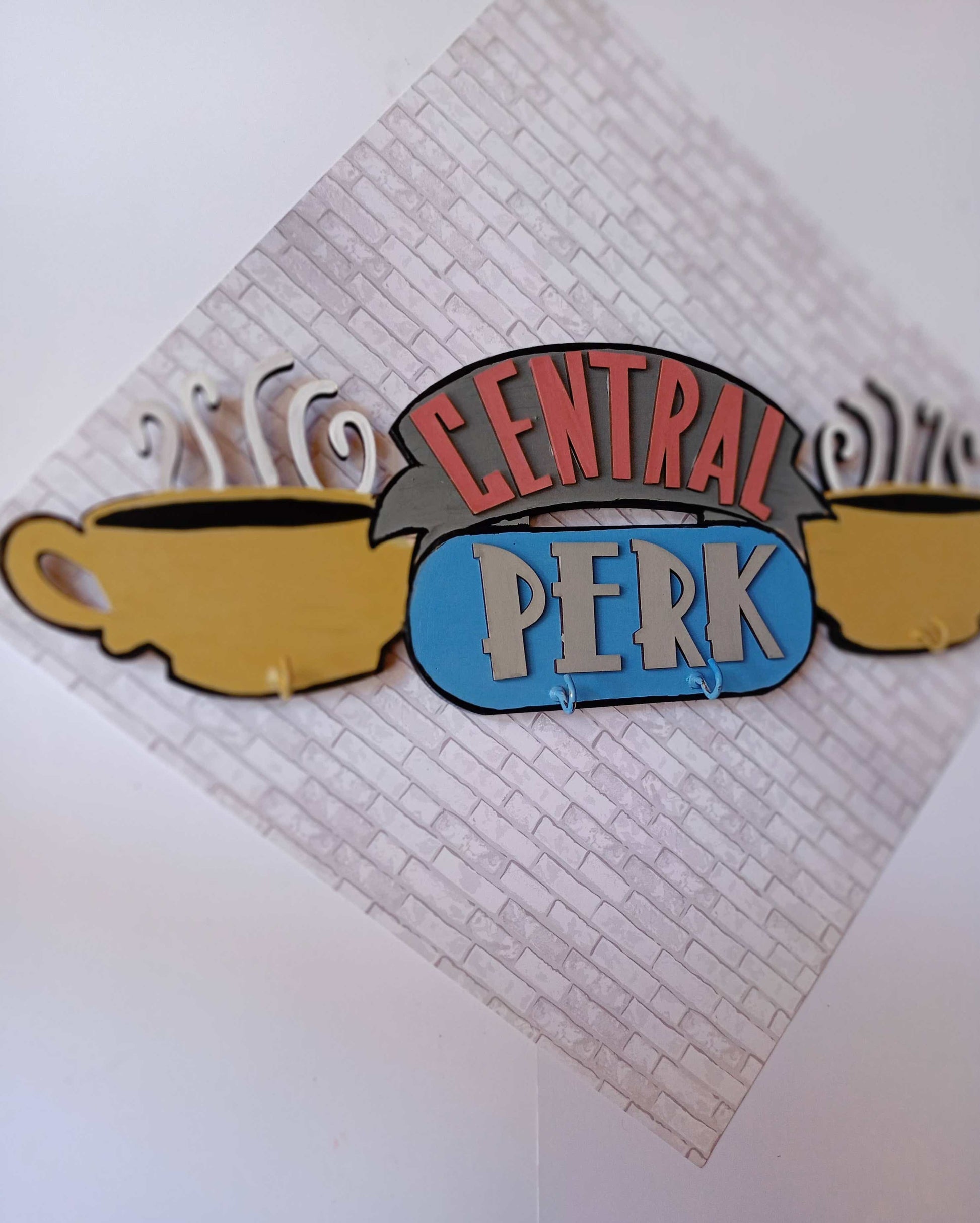 Friends TV central perk logo keyholder in pastel colors on a white wall