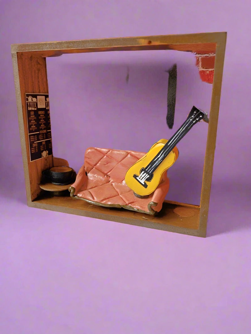 Wooden rectangular frame with miniature orange couch, guitar and friends theme background