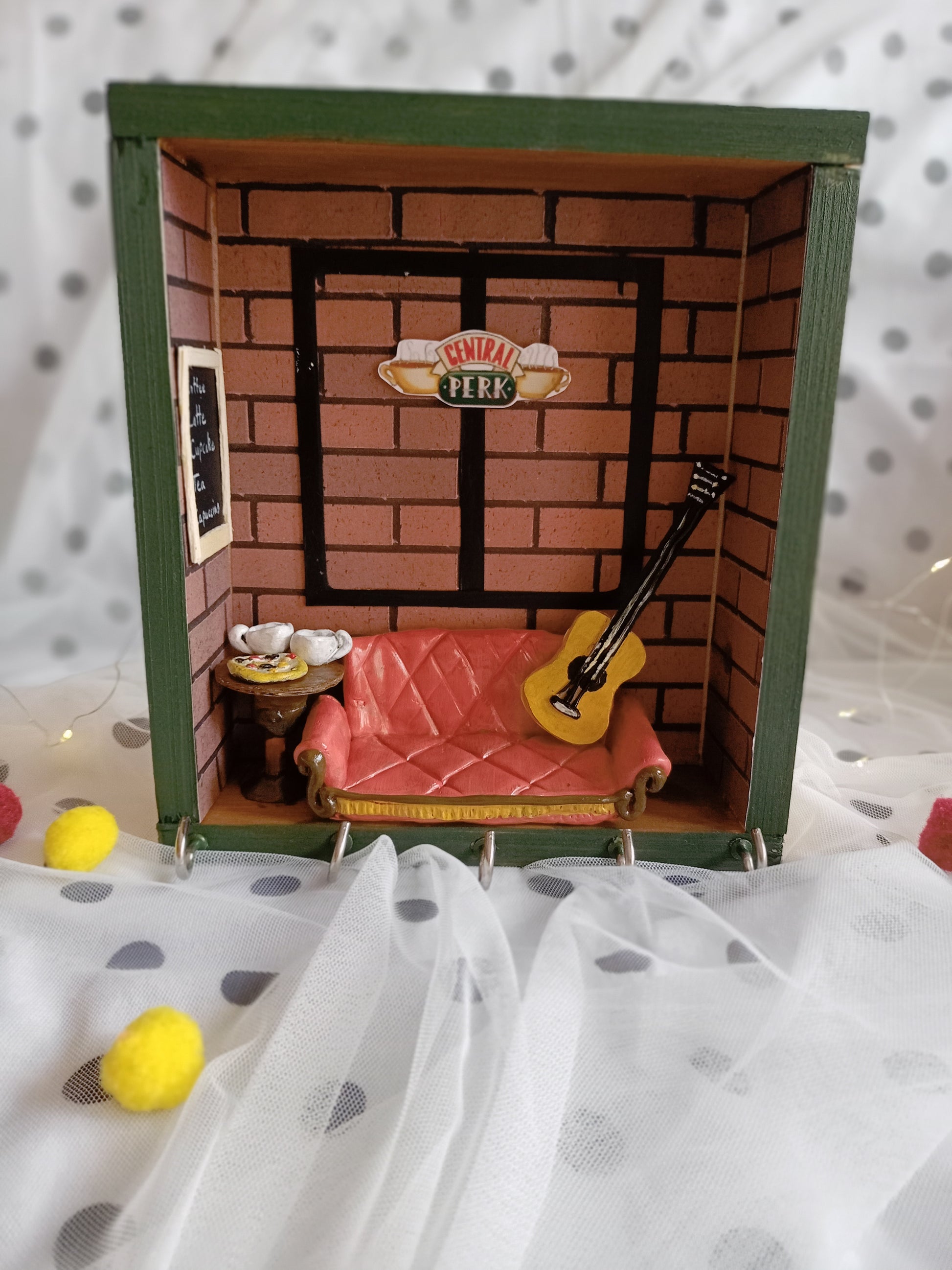 Wooden shadow box frame with orange miniature couch, guitar and central perk theme 