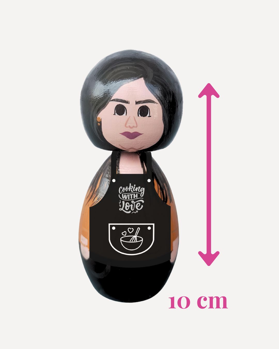 Kokeshi doll with a black apron labeled 'Cooking with Love' and a measurement indicator showing 10 cm.