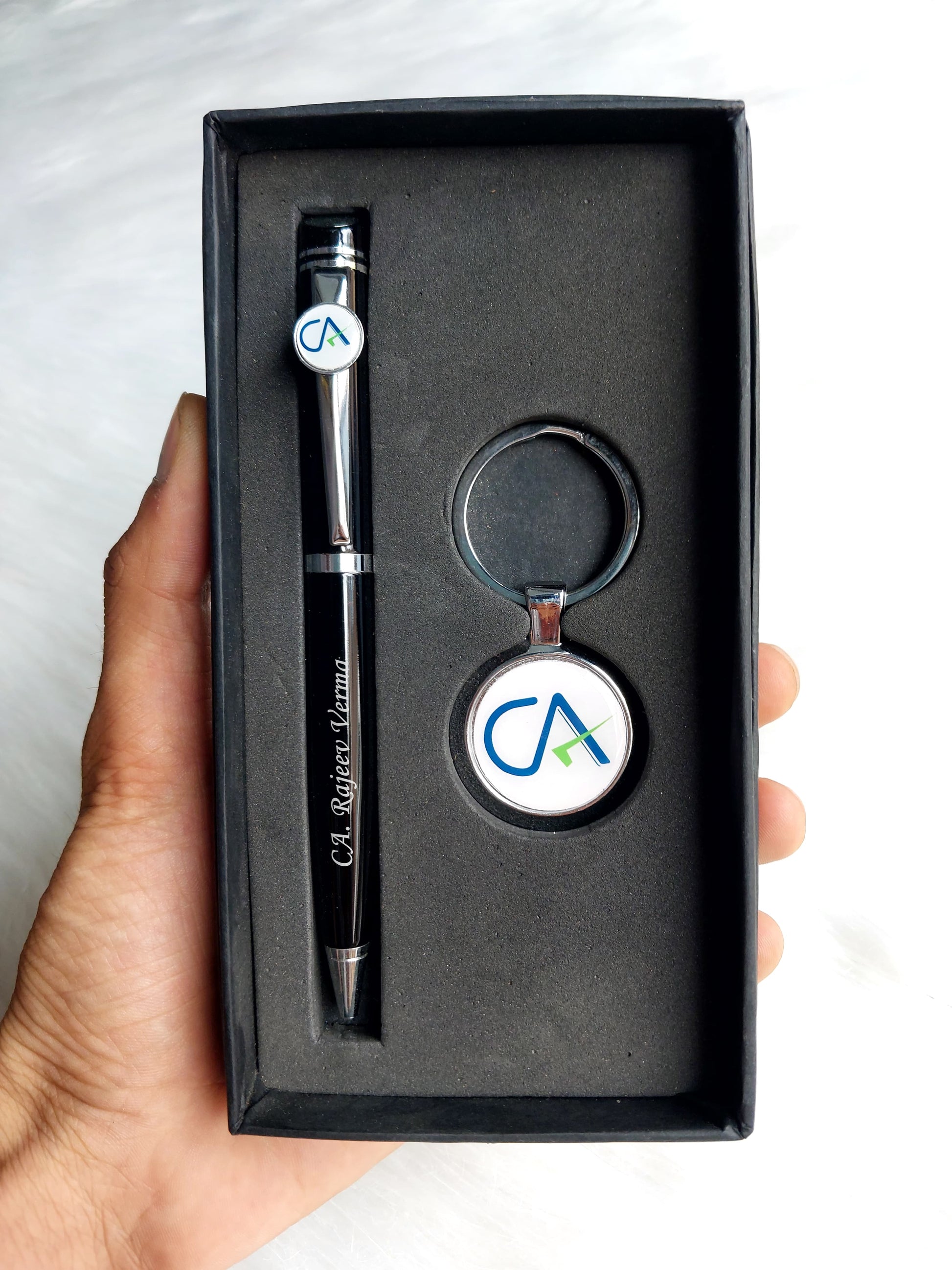 Hand holding Black box with pen and CA keychain inside 