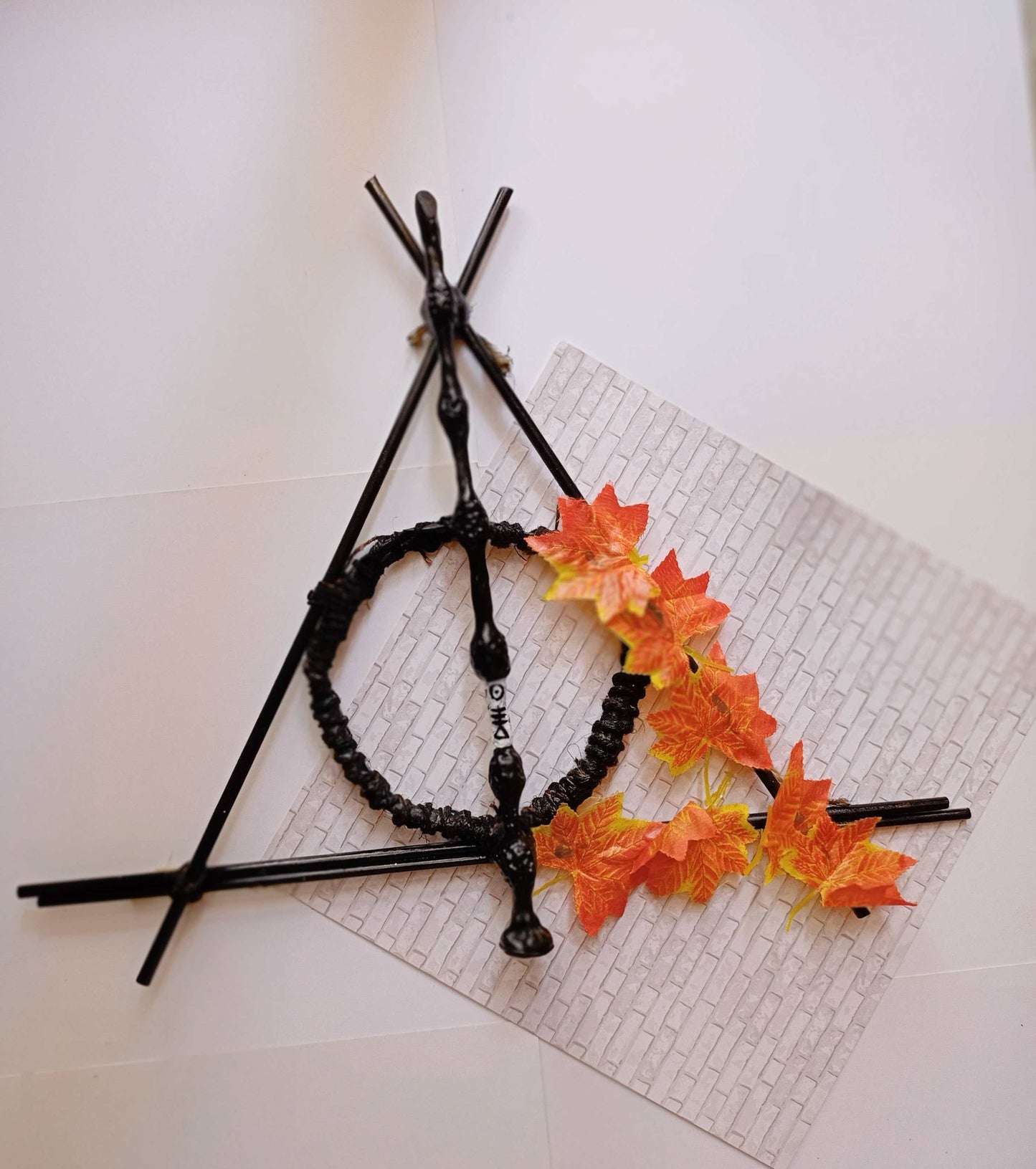 Harry potter deathly hallows sign, elder wand made with wood and decorated with orange leaves 