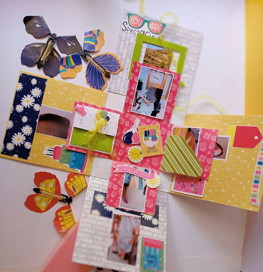 Colorful gift box with photos, flowers and butterfly on a white table