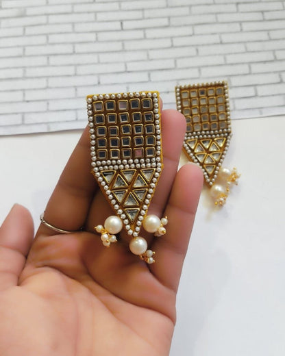 Palm holding Rectangular kundan beaded jhumka earrings on white grey backdrop with pointed bottom