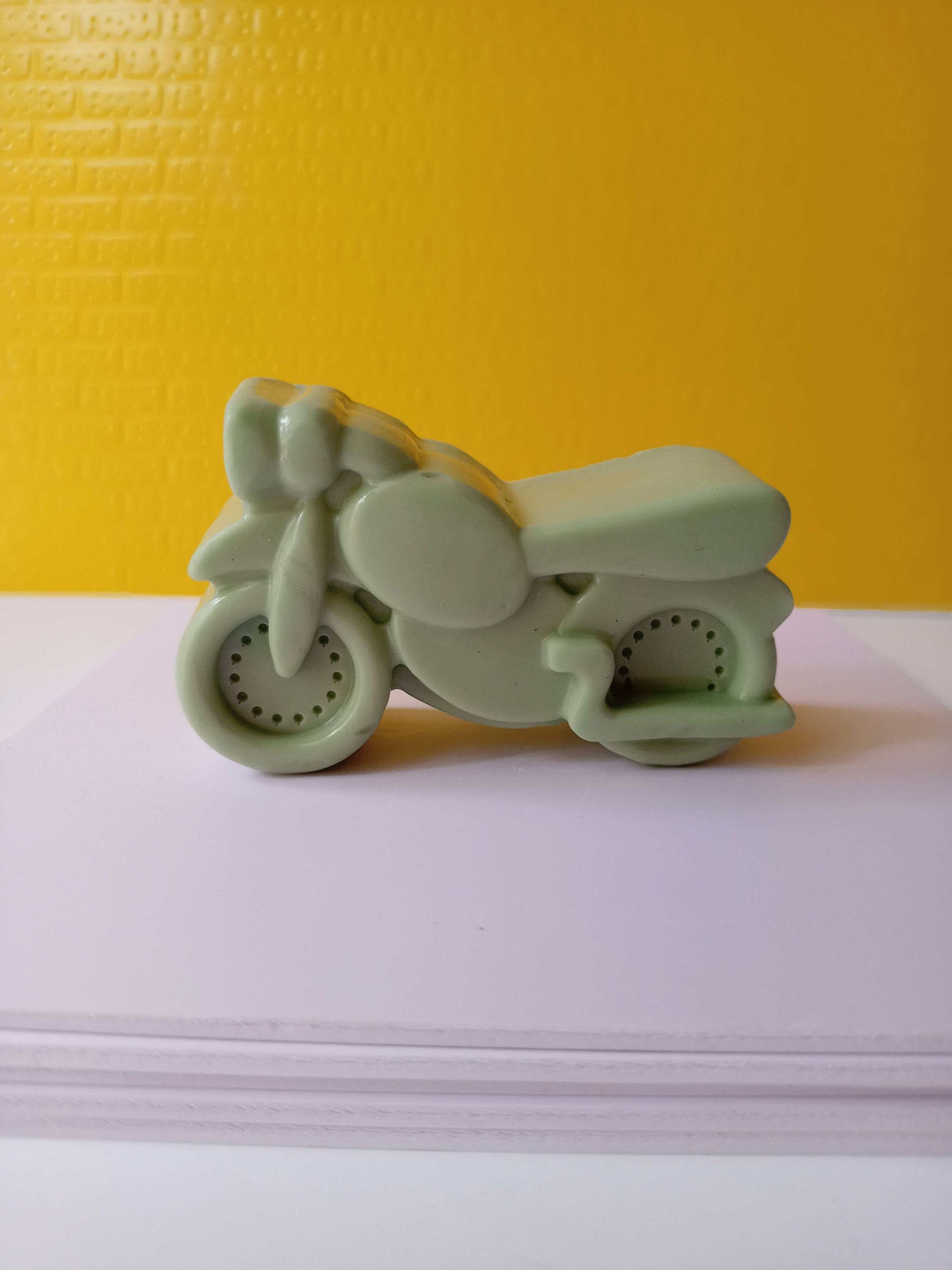 Green motor bike shaped soap on yellow white backdrop