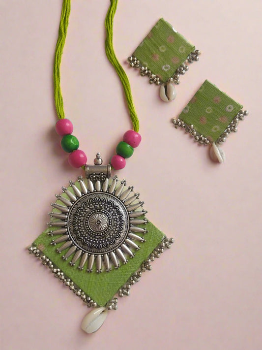 Light green and silver locket necklace with matching earrings on white backdrop