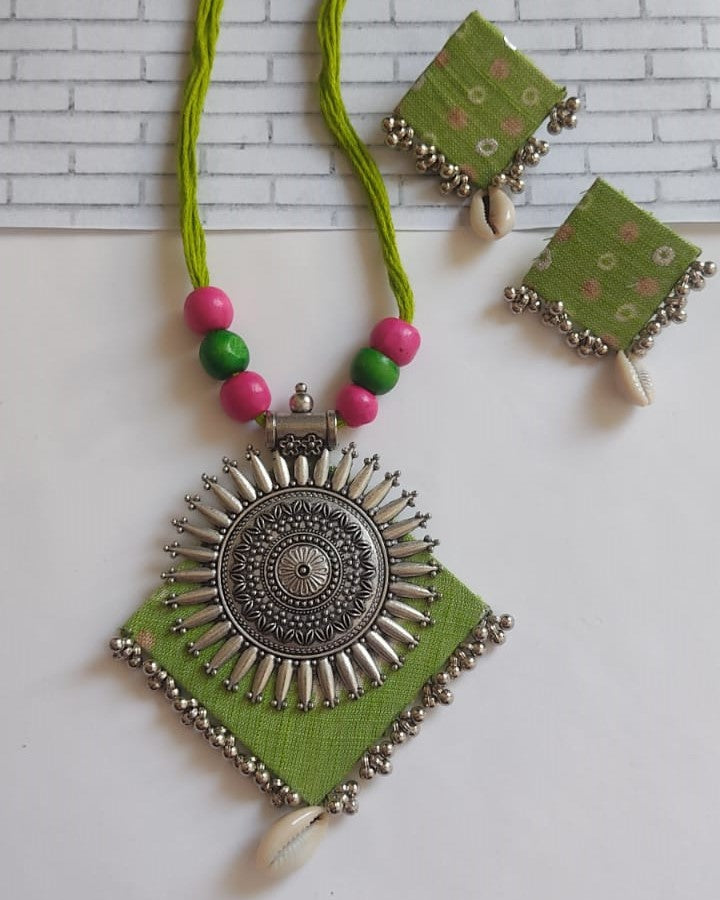 Light green and silver locket necklace with matching earrings on white backdrop
