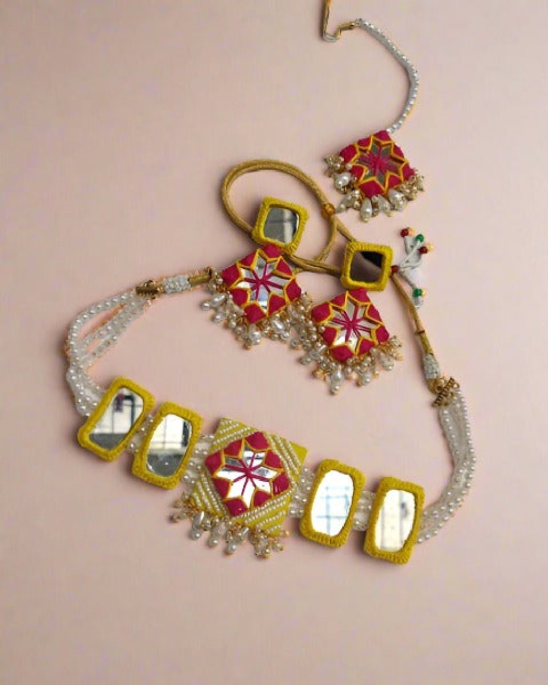 Yellow necklace and earrings set with white and golden beads on white backdrop