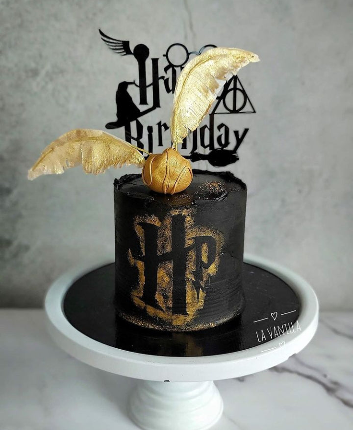 Harry potter cake topper on a black and golden cake