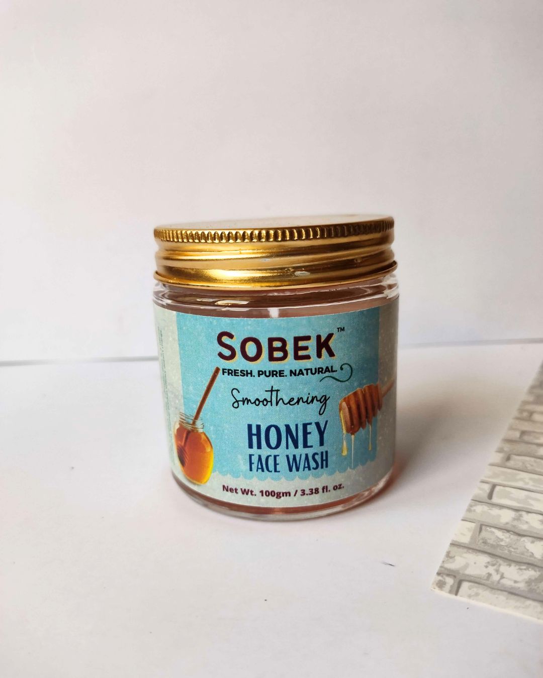 Sobek honey facewash glass jar with golden lid on white wall