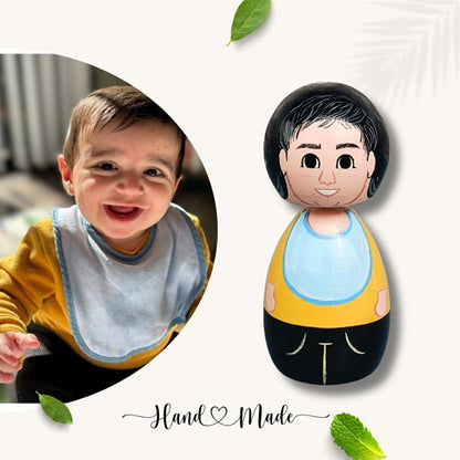 Wooden peg doll of zoobe dolls with yellow and blue outfit with the reference of baby on left 