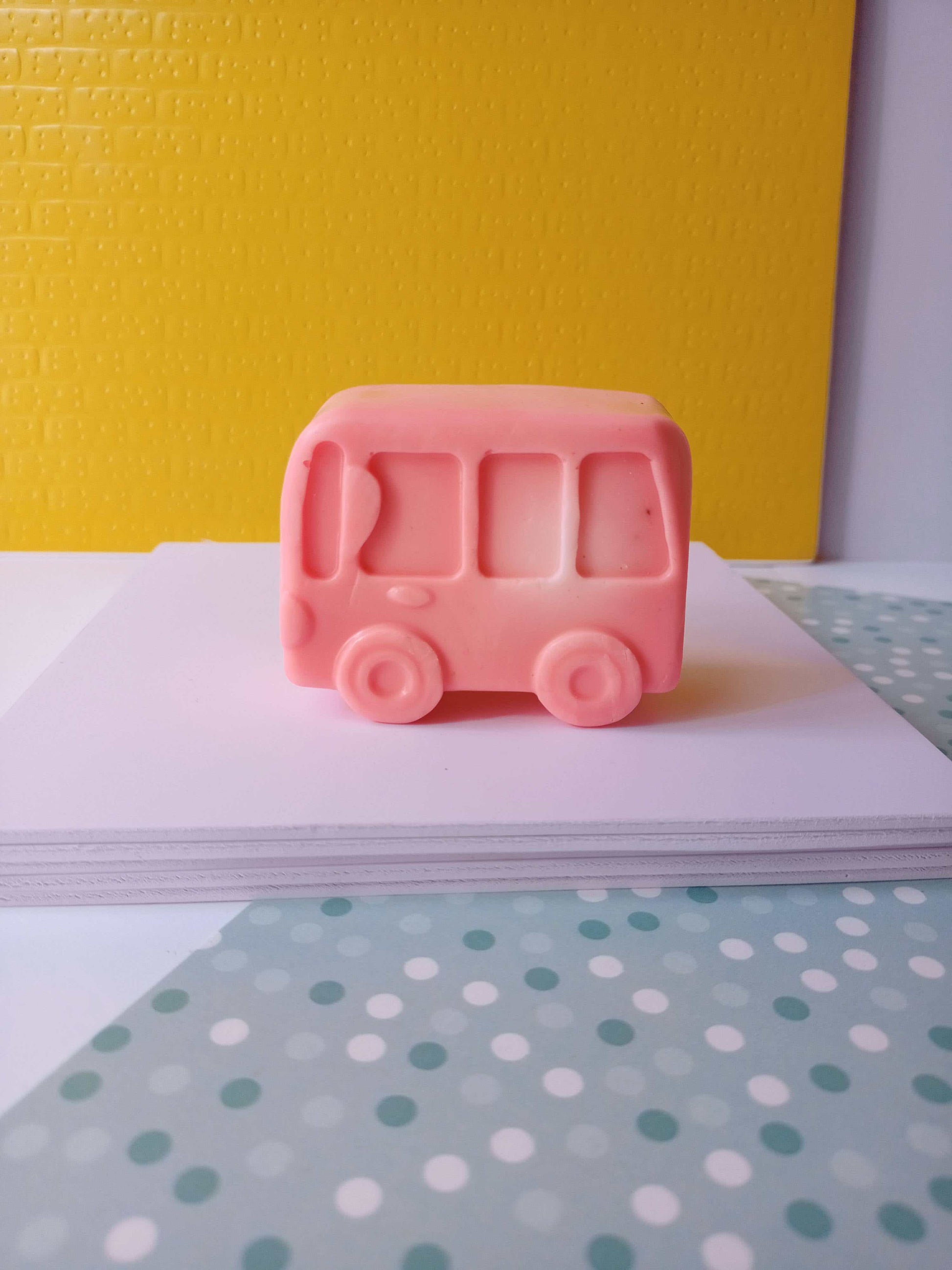Pink bus shaped soap on white and yellow backdrop