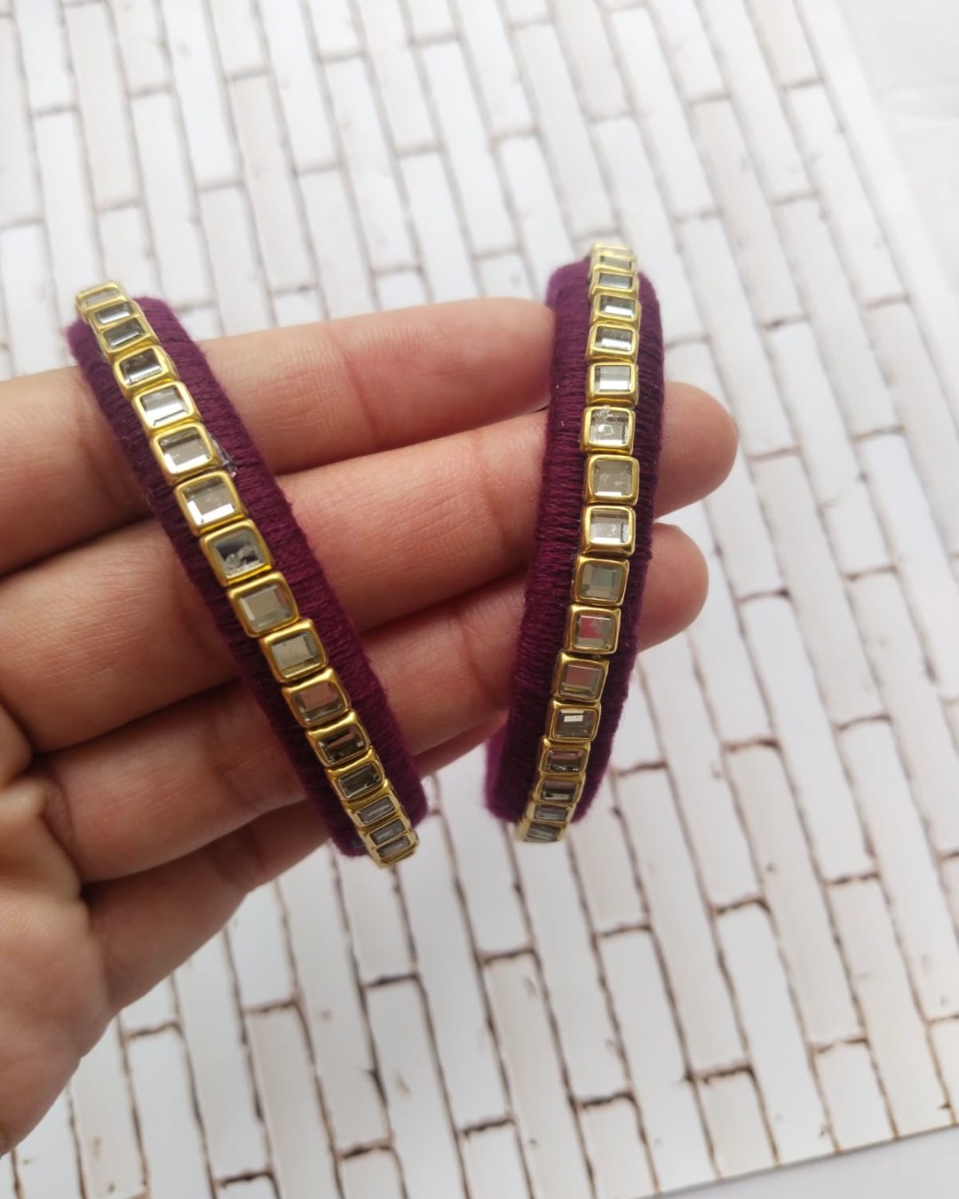 Maroon wine bangles pair with white kundan work on white backdrop