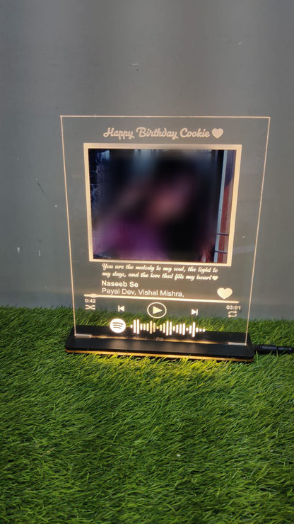 Rectangular LED frame with blurred photo and golden engraving kept on green grass