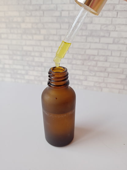 Brown glass jar on white backdrop with its nozzle squeezing yellow oil 