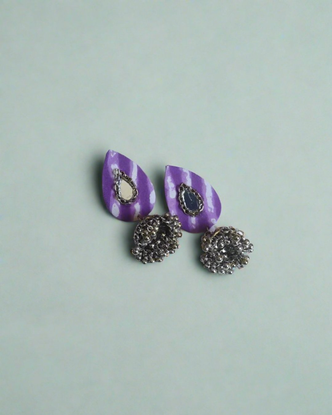 Lavender water drop shaped fabric earrings with jhumki on blue backdrop