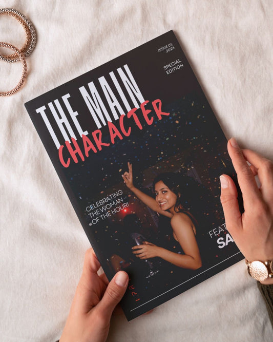 Magazine titled 'The Main Character' held by hands on a light background