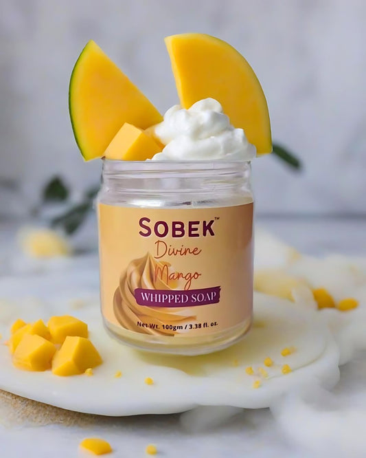Sobek naturals mango whipped cream soap in a jar on white backdrop with mango slices coming out of it