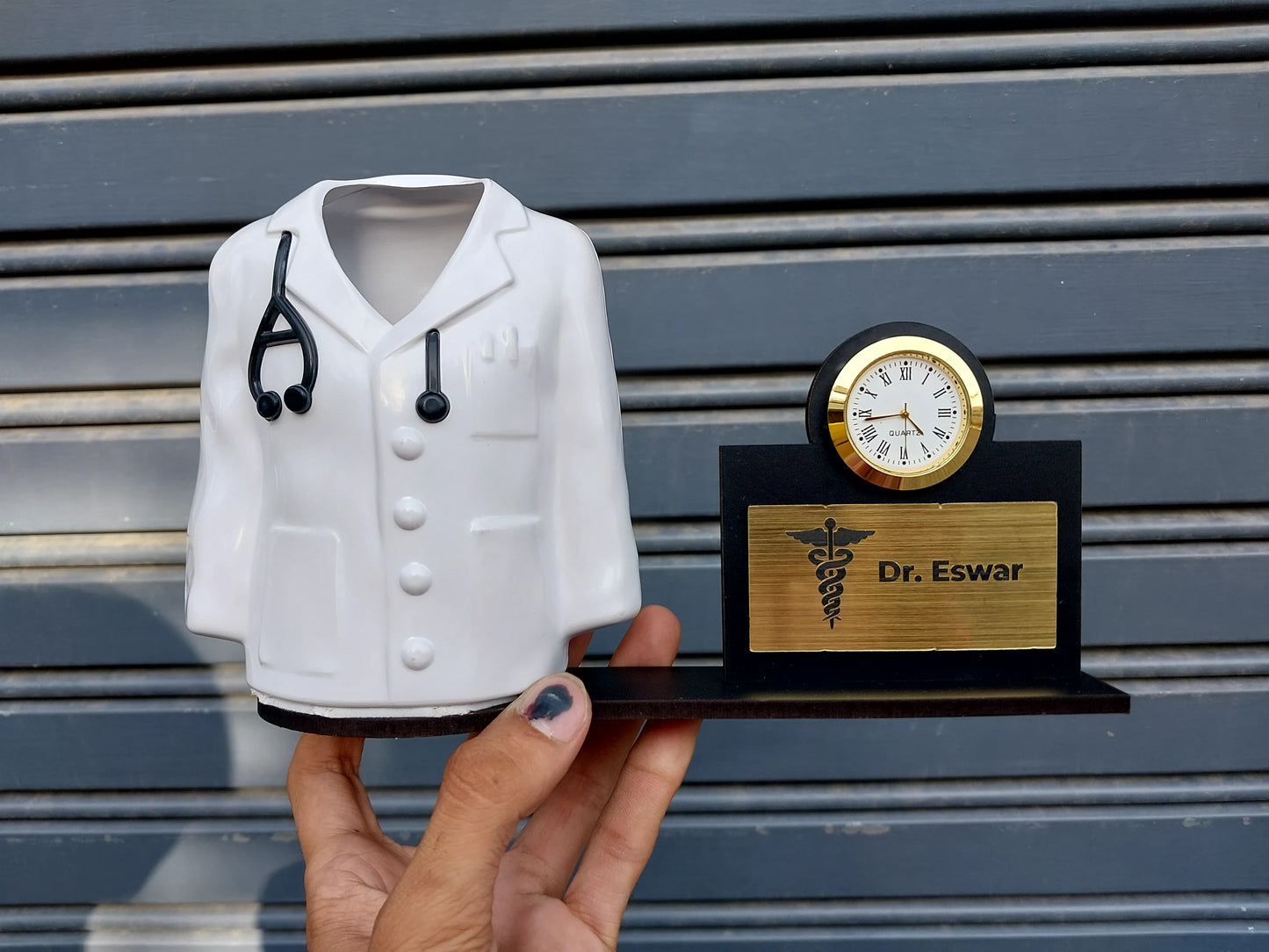 White doctor coat pen stand with golden clock and name of person on right
