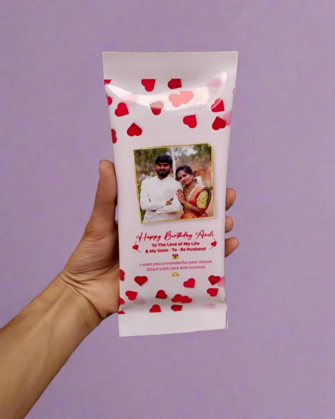 Hand holding pink color cadbury chocolate with couple picture on it