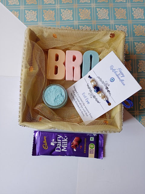 Sis alphabets soaps in pink and blue with dairy milk chocolate and evil eye rakhi inside a golden box