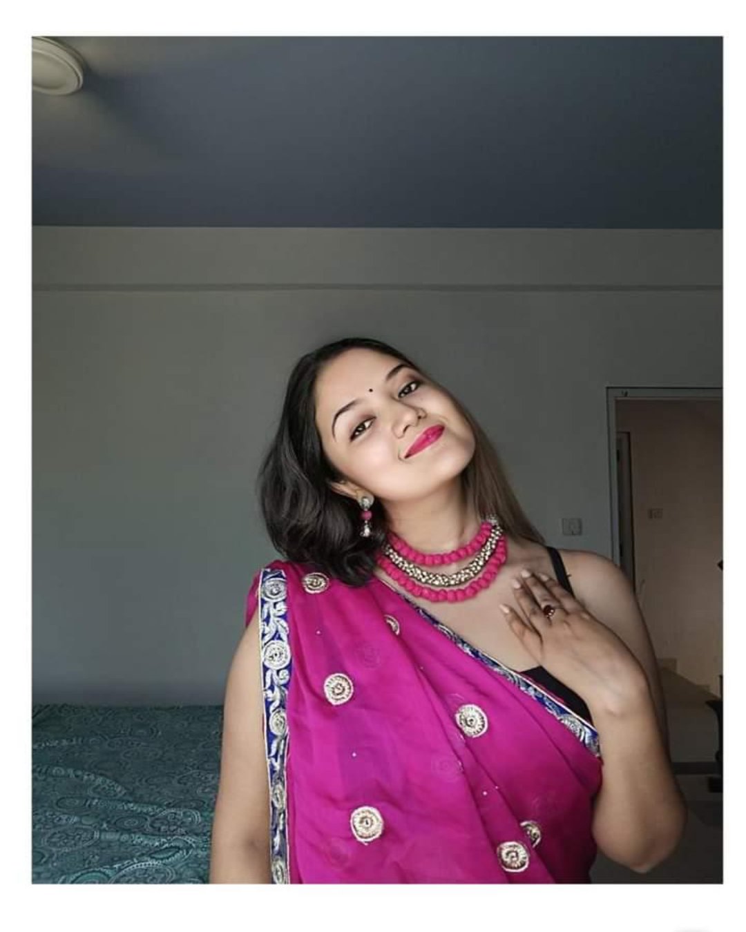 Indian woman smiling wearing a pink saree and pink pom pom choker necklace 