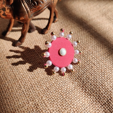Pink finger ring with white pearls border on brown backdrop