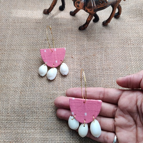 Pink fabric semi circular hoops earrings with white sea shells at bottom 