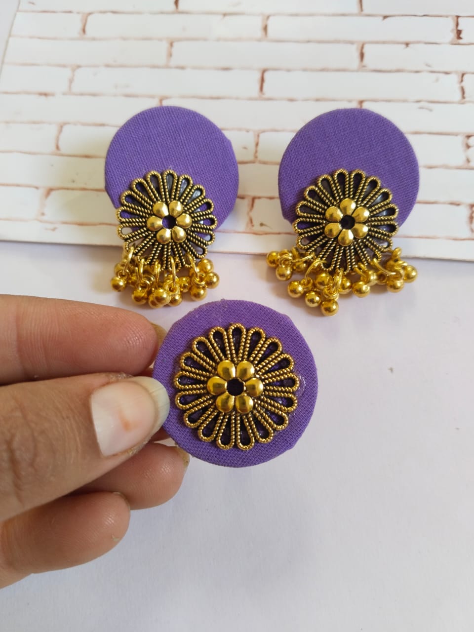 Purple earrings and ring in round shapes with golden charms on white grey backdrop
