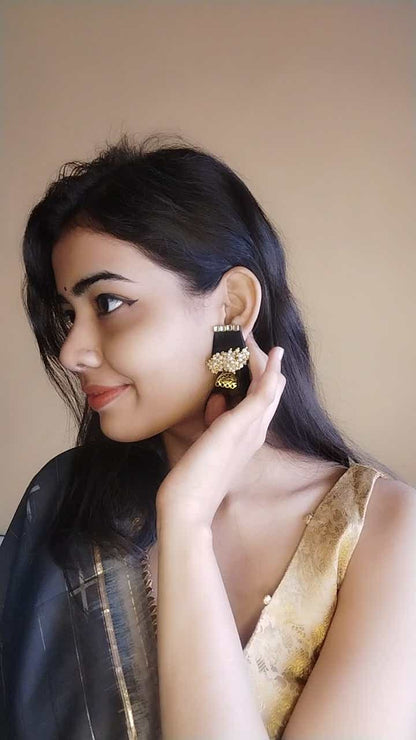 Indian girl smiling wearing black small earrings with golden beads and charm at bottom