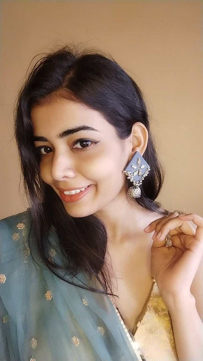 Indian girl smiling wearing dusky blue kite shaped earrings with silver jhumki at bottom