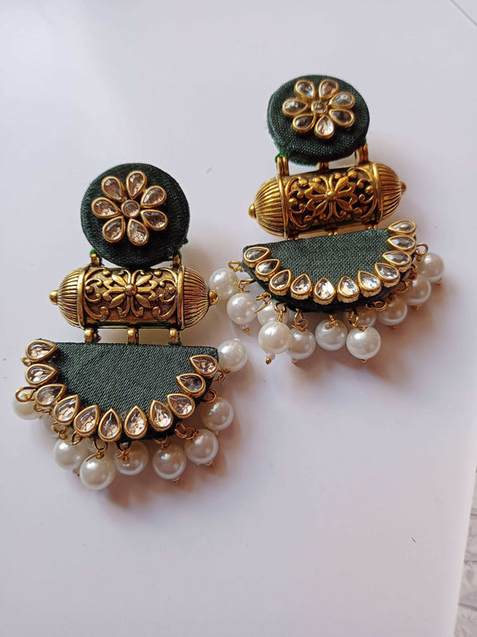 Bottle green earrings with golden kundan and pearls work on white grey backdrop